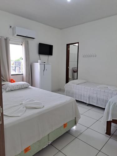 博阿维斯塔Hotel Monte Arau的白色客房的两张床,配有镜子