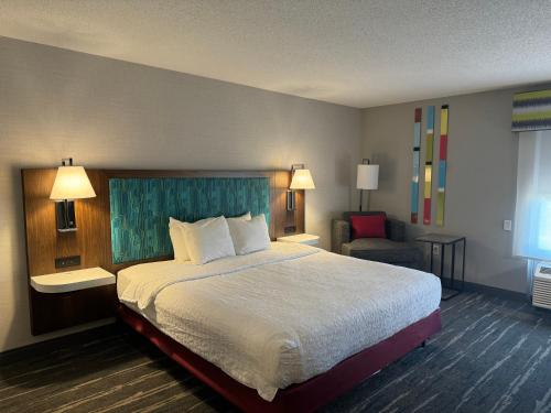 林垦南遗址公园汉普顿酒店的酒店客房带一张大床和一把椅子