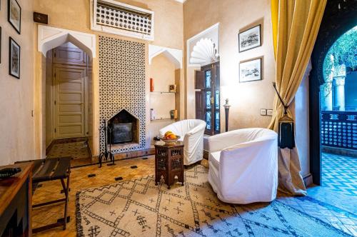 马拉喀什Dar Les Cigognes的客厅配有两把白色椅子和壁炉