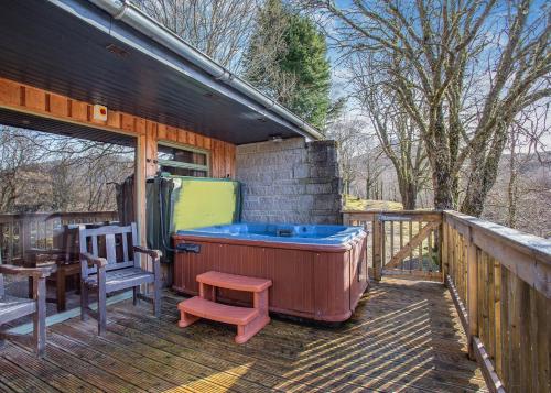 WhitebridgeWildside Highland Lodges的甲板上的热水浴池,配有椅子和桌子