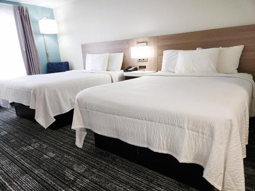 弗利Americas Best Value Inn & Suites-Foley的酒店客房,配有两张带白色床单的床