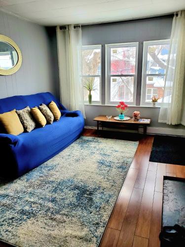 温尼伯Merj's Guest House in Wolesly的客厅设有蓝色的沙发,配有窗户