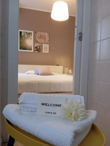 博尔戈马内罗Corte 22 B&b e Appartamenti的配有一张床铺的房间,在长凳上有一个迎宾标志