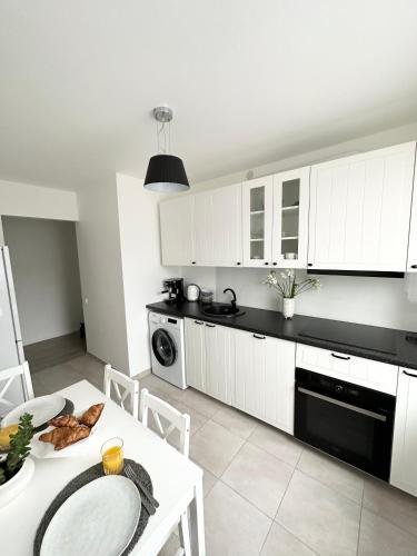 希卢泰Jaukūs apartamentai Šilutėje的厨房配有白色橱柜和白色桌子