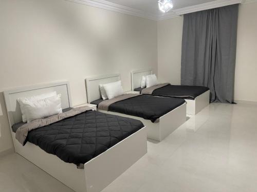 麦地那Almansour Laxury Apartement的白色客房的两张床,配有黑色床罩