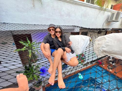 科苏梅尔Hostelito Hotel的两人坐在游泳池旁的围栏上