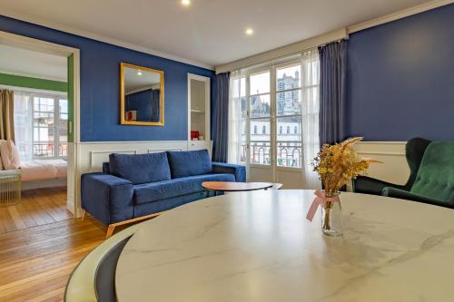 特鲁瓦Aux Deux Clochers de Troyes的客厅配有桌子和蓝色的墙壁