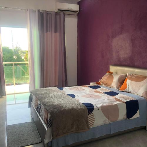 罗安达Guest House Meg Alfa的一间卧室配有一张紫色墙壁的床