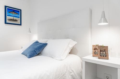 安道尔城AndBnB I Apartamento Céntrico con Terraza y Parking Gratuito的白色卧室配有一张带蓝色枕头的床