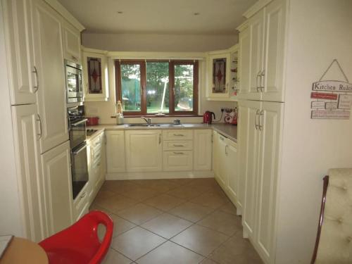 恩尼斯科西Borodino Studio Apartment的厨房配有白色橱柜和红色椅子