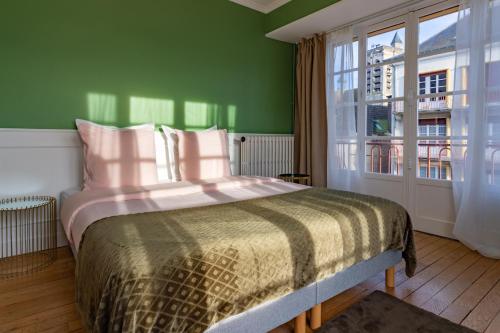 特鲁瓦Aux Deux Clochers de Troyes的一间卧室设有一张带绿色墙壁和窗户的床。