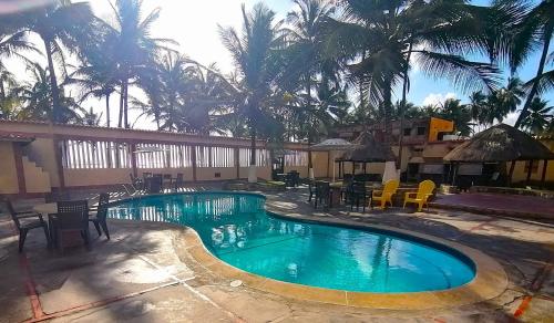 Boca de AroaTucacas, Sotavento的一个带桌椅的游泳池,棕榈树