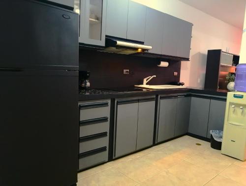 Boca de AroaTucacas, Sotavento的厨房配有白色橱柜和黑色冰箱。