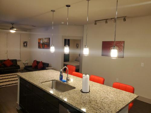休斯顿Smart automation apartment in Woodlake/Westheimer的厨房配有水槽和带红色椅子的台面