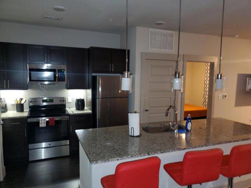 休斯顿Smart automation apartment in Woodlake/Westheimer的厨房配有柜台和红色椅子