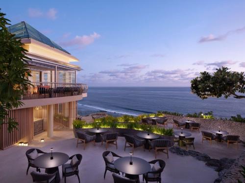 乌鲁瓦图Umana Bali, LXR Hotels & Resorts的一个带桌椅的庭院和大海
