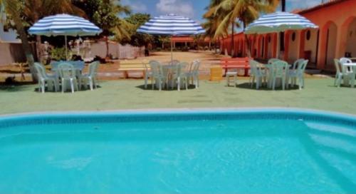 孔迪Pousada Praia Dos Coqueiros的海滩上带椅子和遮阳伞的游泳池