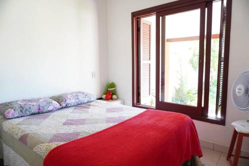 帕苏迪托雷斯Casa aconchegante的一间卧室配有一张带红色毯子的床和窗户。
