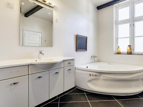 斯文堡20 person holiday home in Svendborg的一间带水槽、浴缸和镜子的浴室