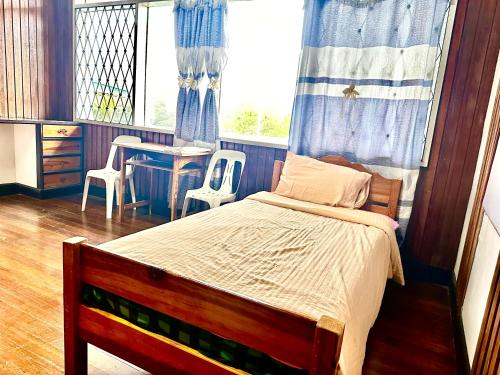 碧瑶Baguio BELL Staycation的一间卧室配有一张床、一张桌子和一个窗户。