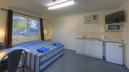 巴卡尔丁Barcaldine Caravan Park的客房设有一张床和一间带窗户的厨房