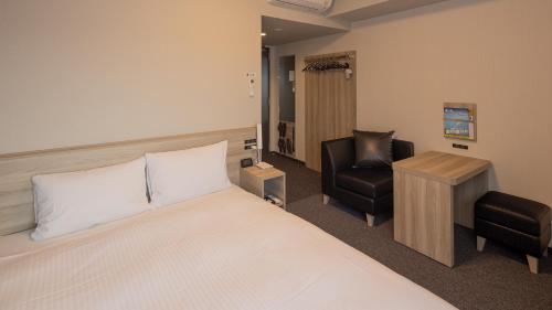 海南市Hotel Route Inn Grand Kainan Ekimae的配有一张床和一把椅子的酒店客房