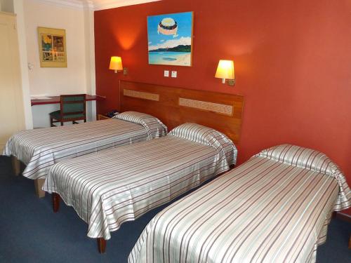 路易港Le Saint Georges Hotel的红色墙壁的酒店客房内的两张床