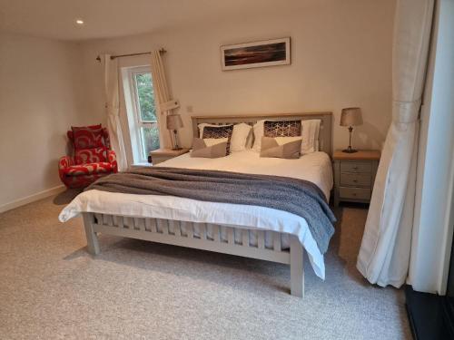 布德Treworgie Barton - Warner的一间卧室配有一张大床和一张红色椅子