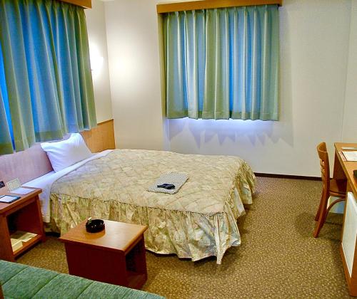米子市Yonago Universal Hotel的酒店客房配有一张床铺和一张桌子。