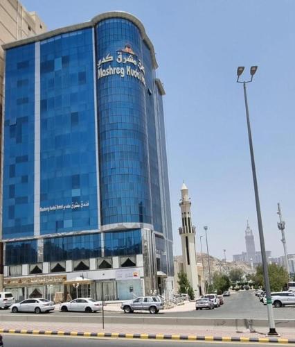 Al Masfalahفندق مشرق كدي的一座蓝色的大建筑,汽车停在停车场