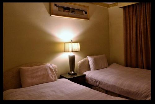Al Masfalahفندق مشرق كدي的酒店客房,设有两张床和一盏灯