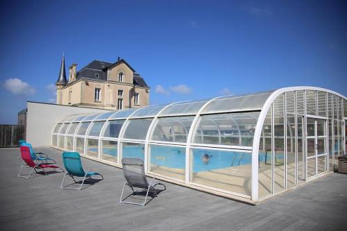 阿内勒Les Tourelles Village de vacances的一座带椅子的玻璃建筑和一座游泳池
