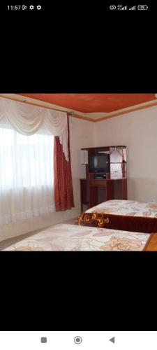 奥塔瓦洛JUYANIS HOSTAL的一间卧室设有一张床、一个窗口和一台电视