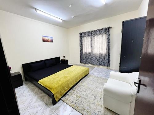 沙迦Sam Home的一间卧室配有黑色的床和黄色毯子