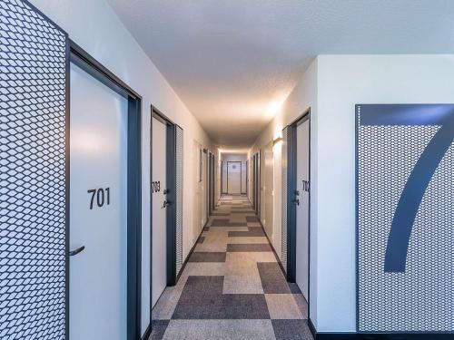 布拉干萨Hotel ibis Bragança的走廊上设有一排门,铺着瓷砖地板