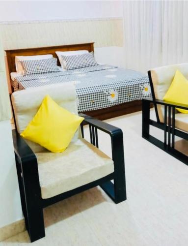 尼甘布JJ Homestay的一间卧室配有一张床和一张带黄色枕头的椅子