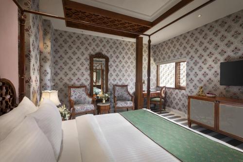 ChirāwaSangam Hotel Marriage Garden & Restaurant的卧室配有床、电视和椅子