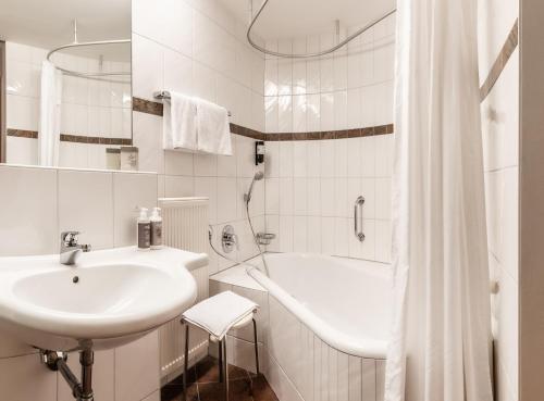 林格瑙Hotel Löwen的白色的浴室设有水槽和浴缸。