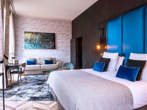 菲雅克Mercure Figeac Viguier du Roy的酒店客房设有一张大床和一张沙发。