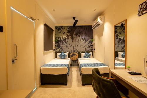 MundraClick Hotel Mundra的酒店客房配有两张床和一张书桌