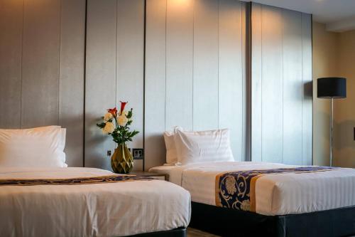 安吉利斯Hevea Hotel & Resort的花瓶间内的两张床
