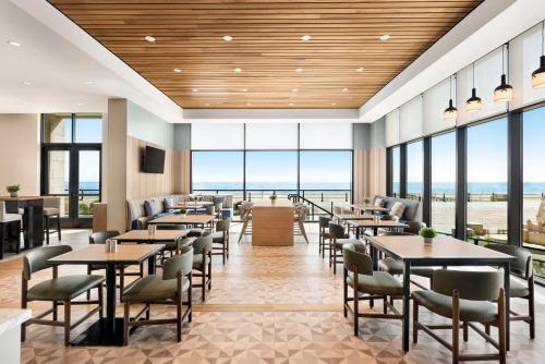 弗吉尼亚海滩Hyatt Place Virginia Beach Oceanfront的餐厅设有桌椅和大窗户。