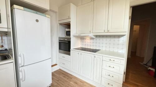 奥斯陆Oslo-Frogner的白色的厨房配有白色橱柜和冰箱。