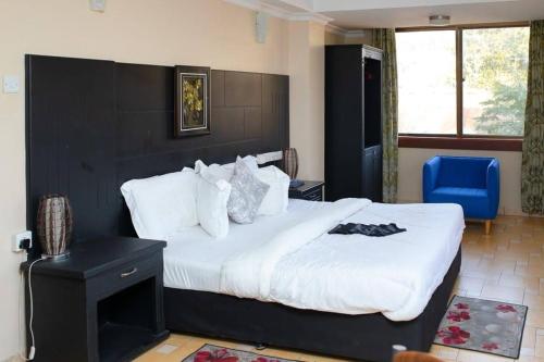 姆万扎Hotel Kingdom的一间卧室配有一张大床和一张蓝色椅子