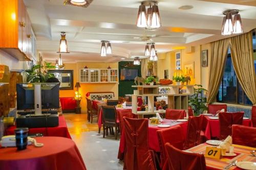 姆万扎Hotel Kingdom的餐厅设有红色的桌椅和电视。