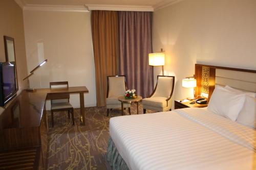 利雅德利雅得爱慕酒店的配有一张床和一张书桌的酒店客房