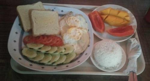 爱妮岛Kubo Inn & Beach Camp的盘子,盘子上放着一盘食物,包括面包和水果