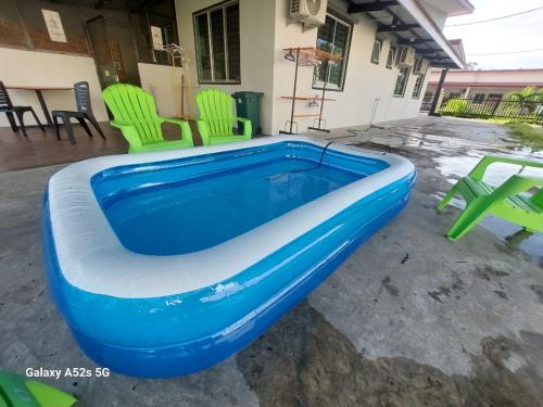 古达S99 HOMESTAY KUDAT的庭院内带绿色椅子的蓝色游泳池