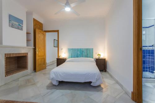 圣玛丽亚港Azvalia Valdeazahares的一间白色卧室,配有一张床和一个壁炉