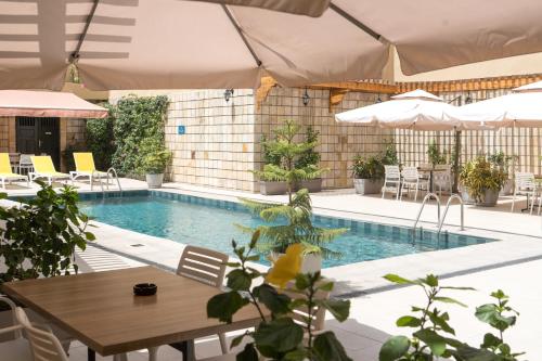 达喀尔Hôtel AL AFIFA的一个带桌椅和遮阳伞的游泳池